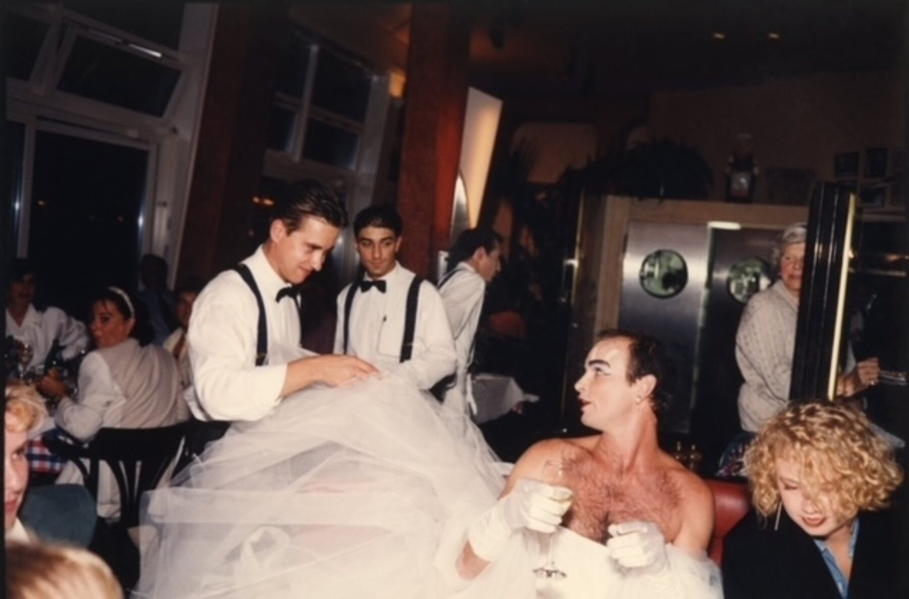 Photograph of a person in a tuxedo at a restaurant, holding a piece of sheer fabric.